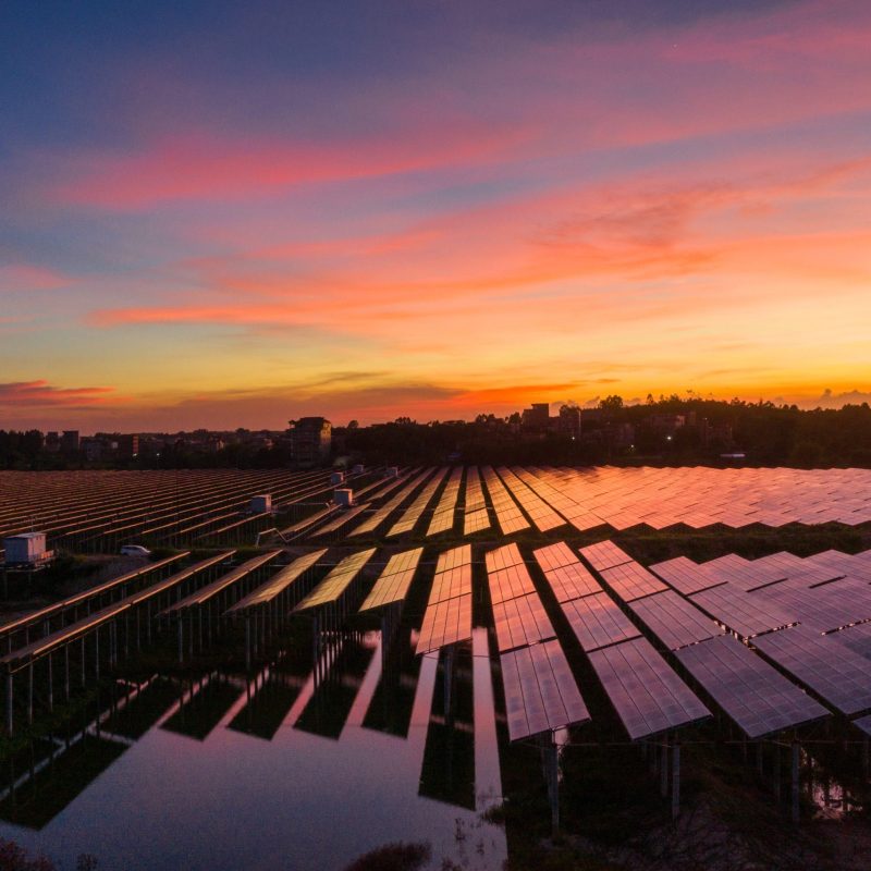 Solar panels reflecting the sunset over a water surface, demonstrating sustainability in energy production.